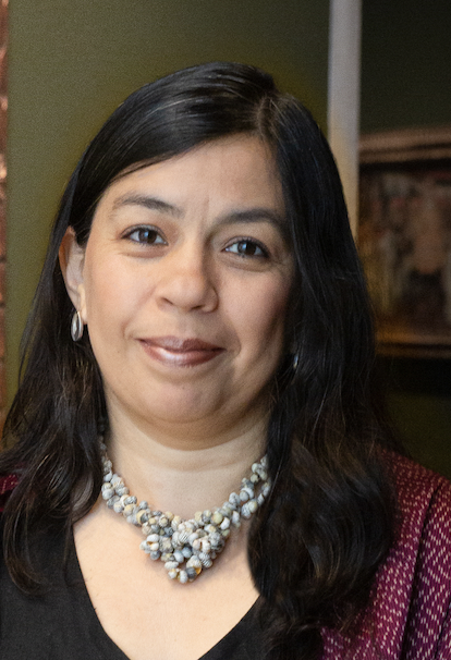 A headshot of a woman smiling, behind her is a painting from colonial Spanish America..