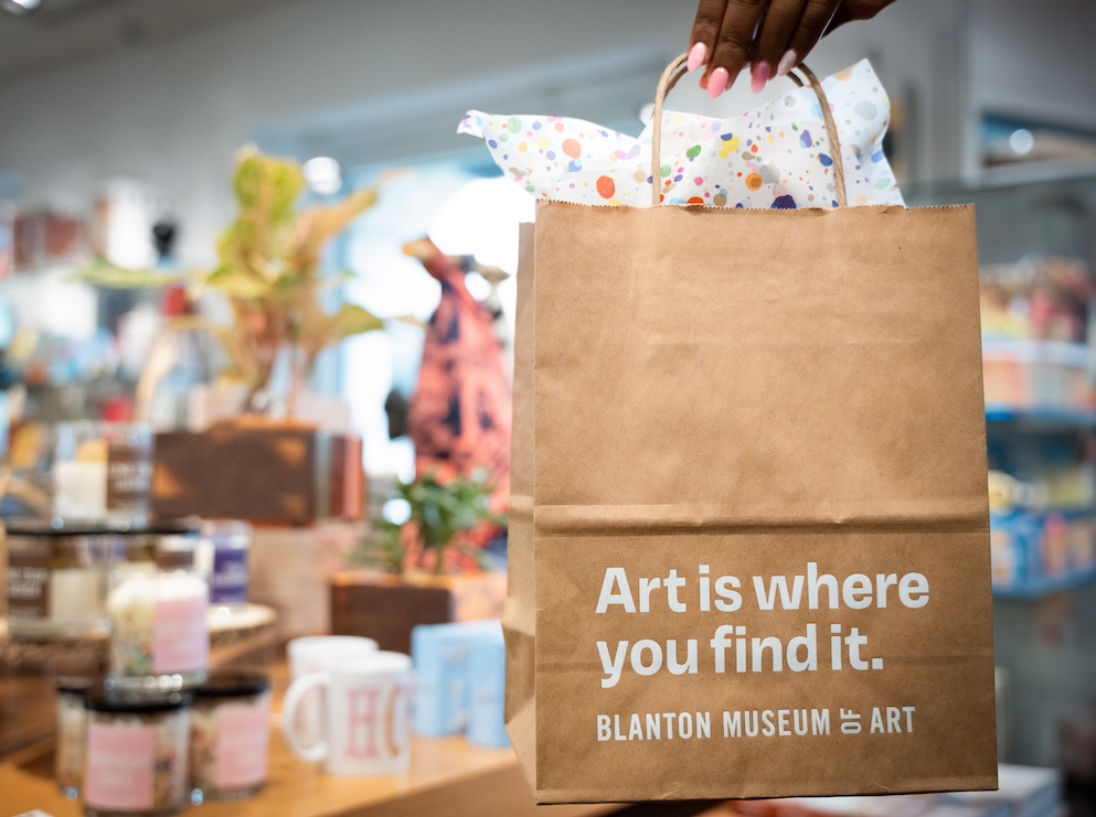 A hand holding a paper bag which reads "Art is where you find it"