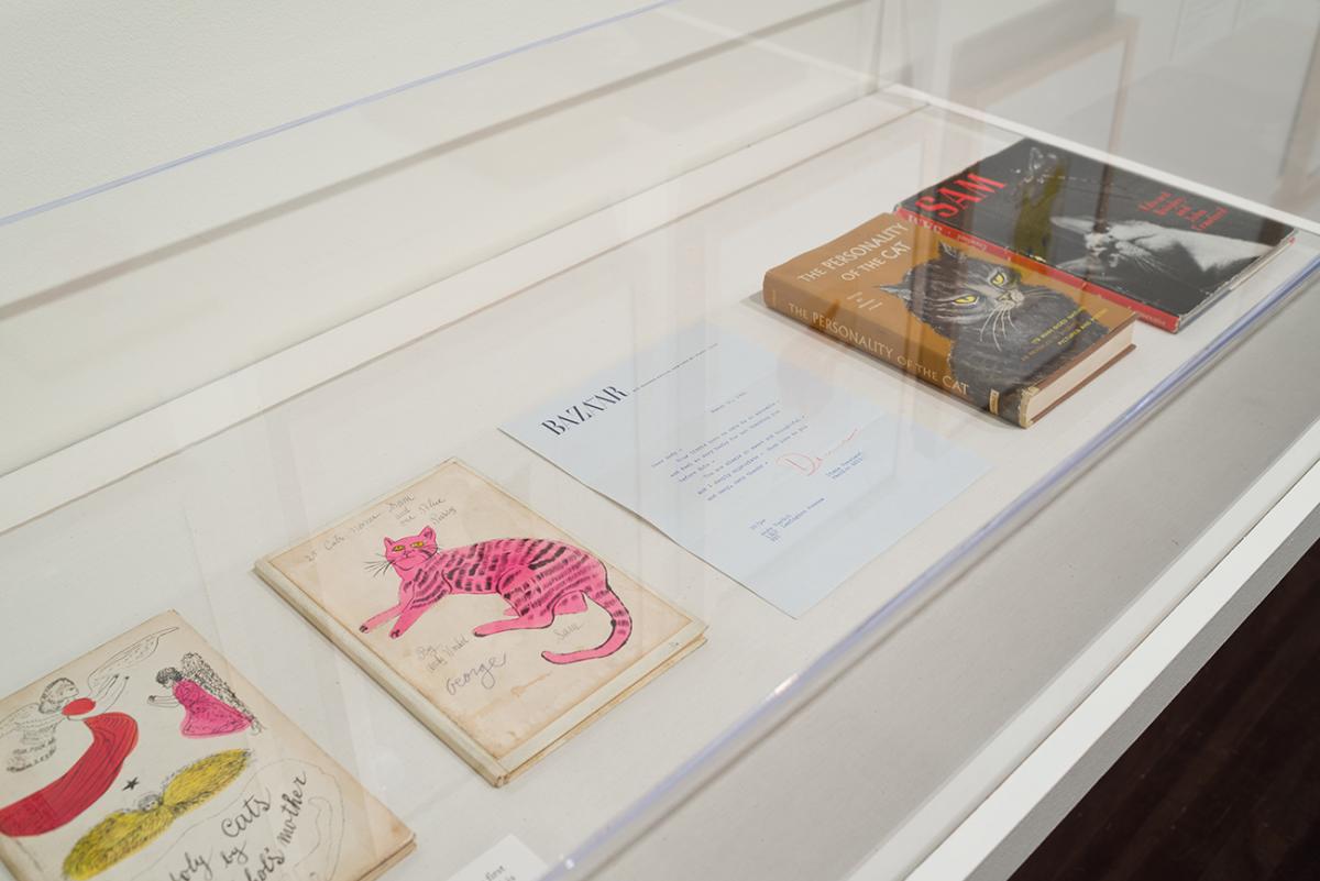 Printed books featuring illustrations of cats and a typed letter in a case